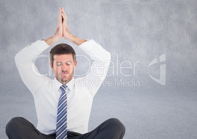 Business man meditating with hands over head against grey wall