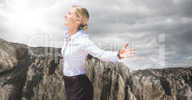 Business woman enjoying sun against rock and cloudy sky