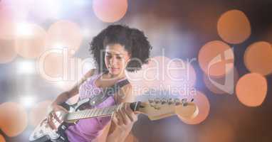 Confident female music artist playing guitar over bokeh