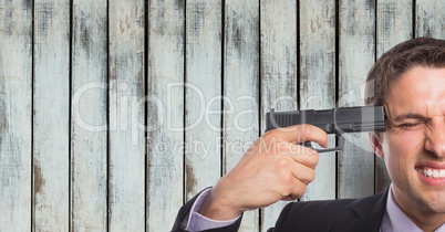 Businessman shooting himself against wooden wall