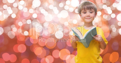 Cute boy holding book against bokeh