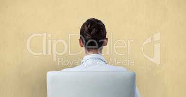 Rear view of businesswoman sitting on chair against wall