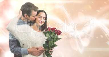 Loving man kissing woman holding roses over bokeh