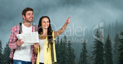 Woman pointing while man holding map during traveling on mountain in foggy weather