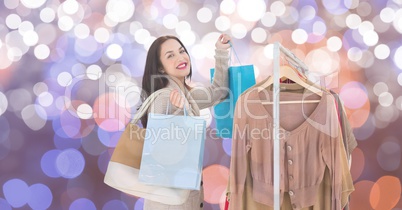 Happy woman shopping by clothes rack over blurred background