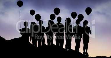 Silhouette children with balloons on hill against sky