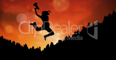Businesswoman holding megaphone while jumping on mountain during sunset