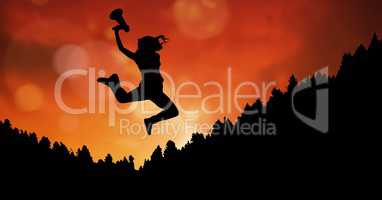 Businesswoman holding megaphone while jumping on mountain during sunset