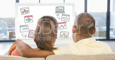Rear view of couple looking at various icons on desktop pc while sitting at home