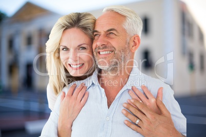 Happy woman embracing man against house