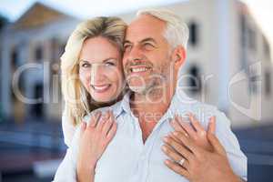 Happy woman embracing man against house