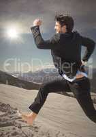 Business man jumping on mountain with sun flare