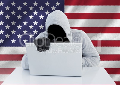 Anonymous Criminal in hood with laptop in front of American flag