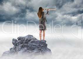 Business woman with telescope on mountain peak against storm clouds