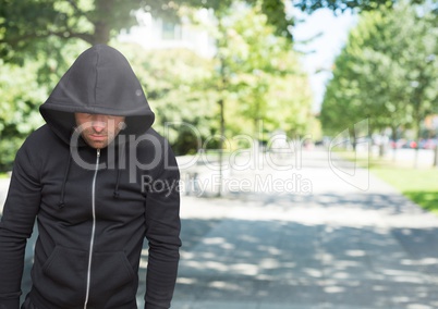 Criminal in hood in front of park