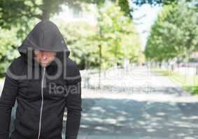 Criminal in hood in front of park