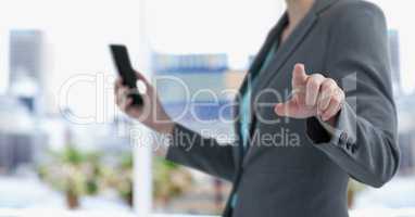 Midsection of businesswoman holding smart phone while pointing in city