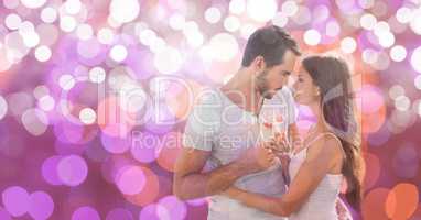 Passionate young couple holding champagne flutes over bokeh