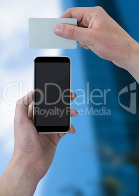Hand with phone and card against blurry building