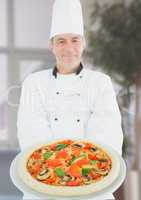 Chef with pizza in the restaurant. Blurred background