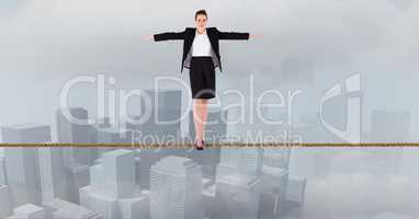 Businesswoman with arms outstretched standing on rope over city