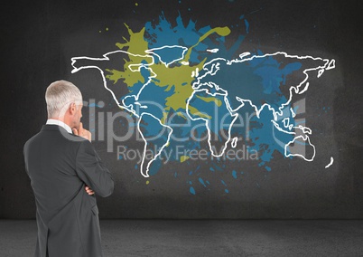 Businessman looking at Colorful Map with paint splatters on wall background