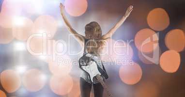 Rear view of music artist with arms raised over bokeh