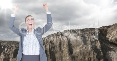 Business woman cheering with flare against rock and cloudy sky