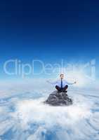 Business man meditating on mountain peak in the clouds