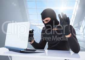 Criminal in hood with laptop in front of window