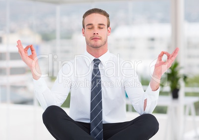 Business man meditating in blurry office