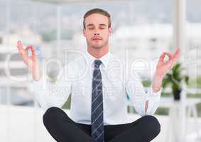 Business man meditating in blurry office