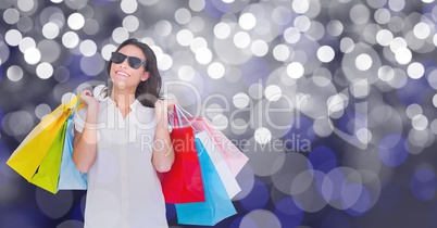 Happy woman carrying shopping bags over bokeh