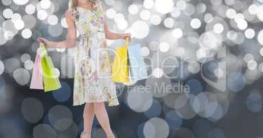 Midsection of woman holding shopping bags over bokeh