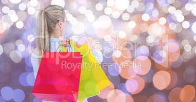 Rear view of woman with multi colored shopping bags over bokeh