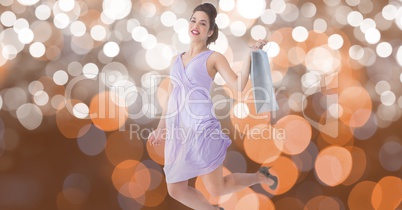 Excited woman holding shopping bag while jumping over bokeh