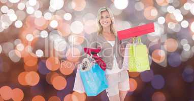 Smiling woman with shopping bags and boxes over bokeh