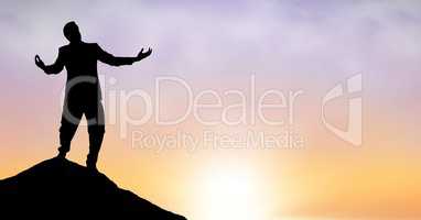 Silhouette businessman with arms outstretched standing on peak