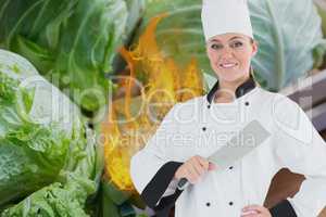 Portrait of chef holding kitchen knife with fire and vegetables in background