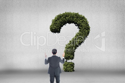 Businessman looking at question mark made of bushes