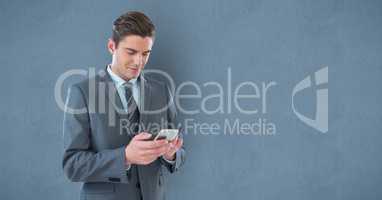 Businessman texting on smart phone against wall