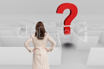 Rear view of businesswoman with hands on hips looking at question mark over maze
