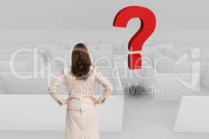 Rear view of businesswoman with hands on hips looking at question mark over maze