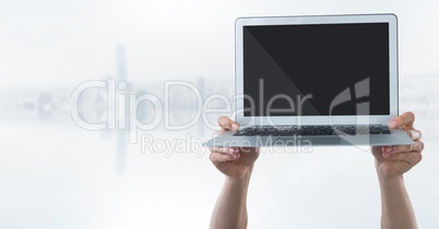 Hands with laptop and flare against blurry white skyline