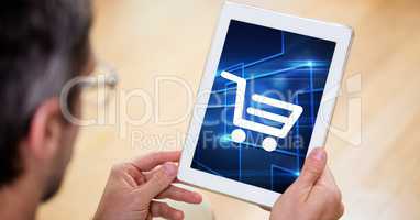 Man looking at shopping cart icon on digital tablet screen
