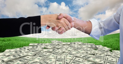 Close-up of handshake with money in background