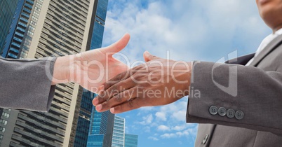 Close-up of business people shaking hands in city