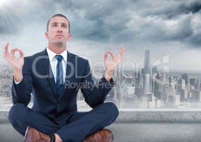 Business man with flare meditating against grey skyline and clouds