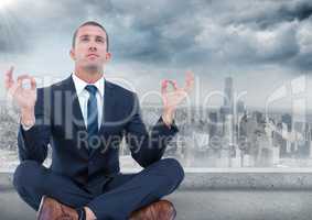 Business man with flare meditating against grey skyline and clouds