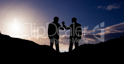 Businesspeople holding hands on mountains against sky